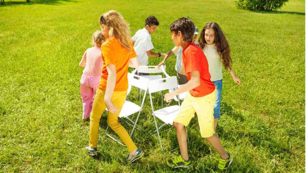 A group of young people playing musical chairs outdoors